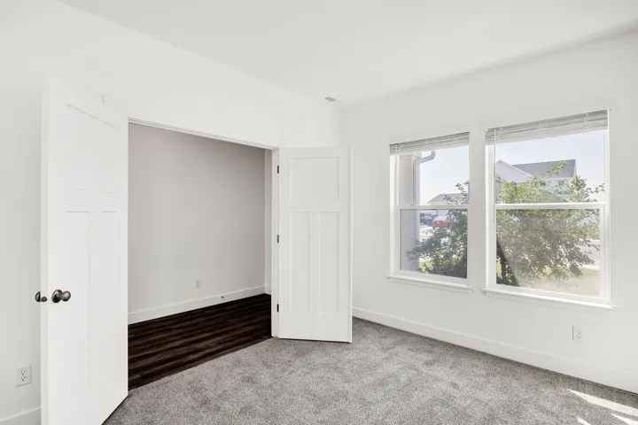 Bright corner bedroom with dual windows, neutral wall finishes, and plush carpeting