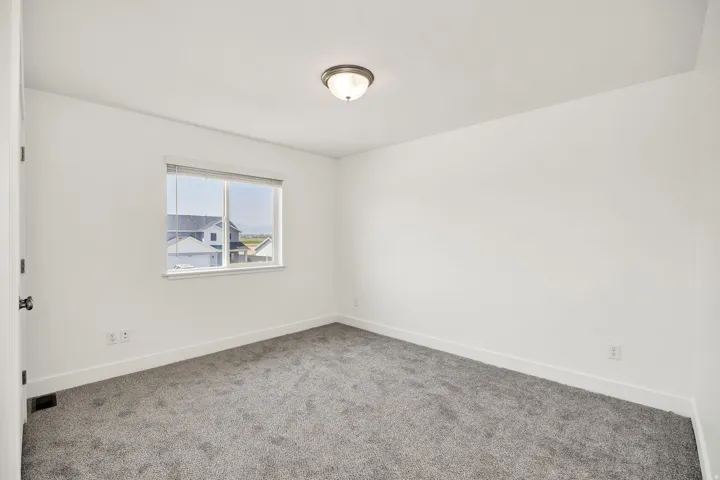 Neutral wall tones, gray carpeting, and a window with blinds