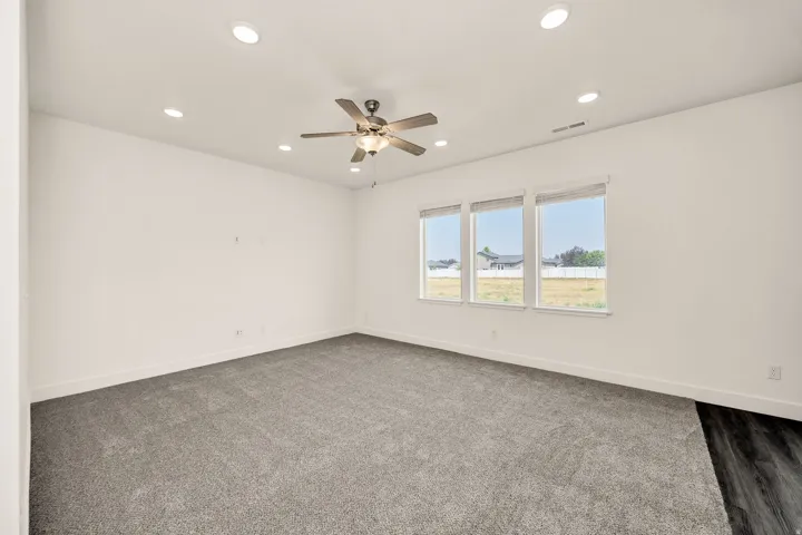 Recessed ceiling lighting, ceiling fan fixture, triple windows, and plush grey carpeting