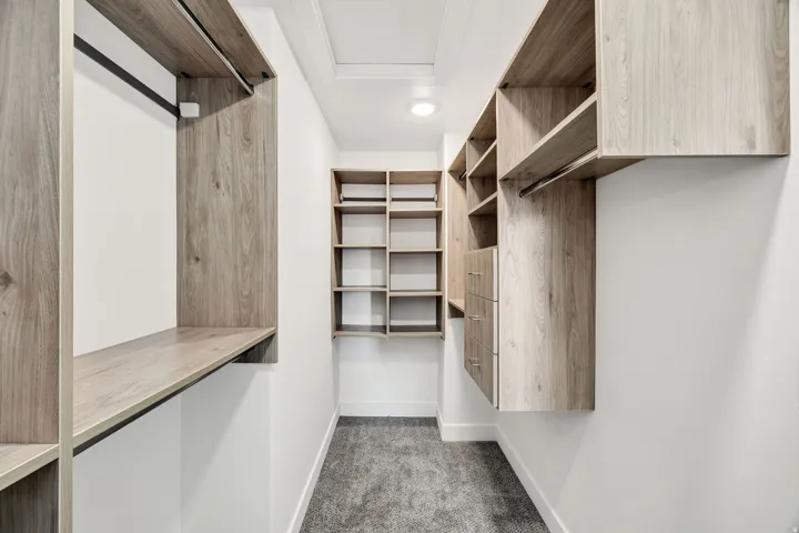 Walk-in closet with integrated wood-finish shelving, built-in drawers, and hanging rods
