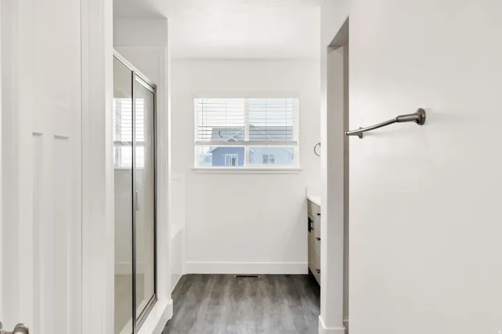 Bright hallway with wood-finish flooring, white shaker-style cabinetry, and multiple windows providing natural light