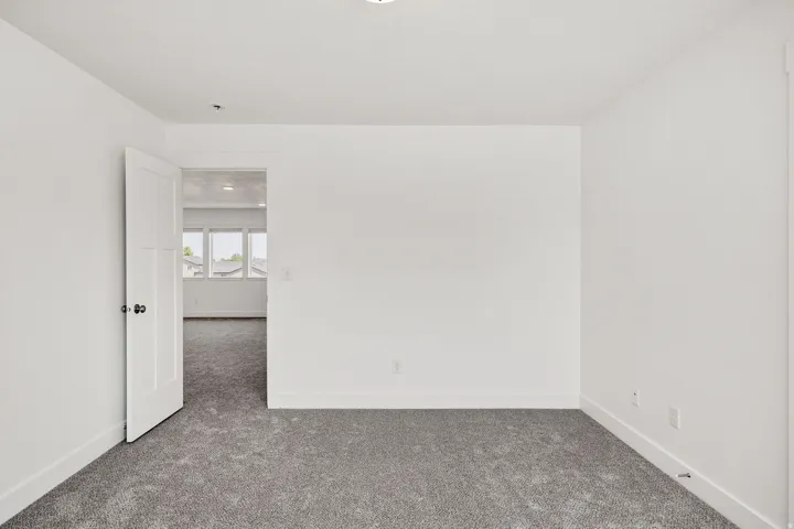 Bright, open bedroom with neutral wall finishes, recessed ceiling lighting, and plush carpeting throughout