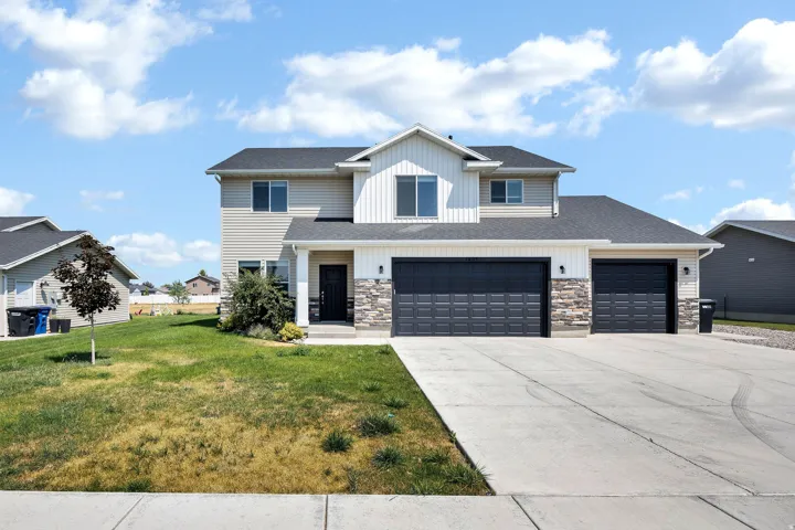 Two-story residence featuring siding and stone facade, a two-car garage, and a concrete driveway