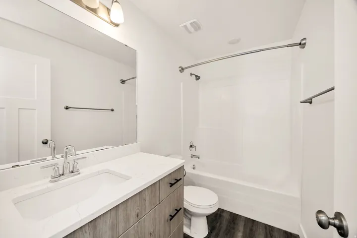 Vanity with wood-finish cabinetry, white countertop, and integrated sink