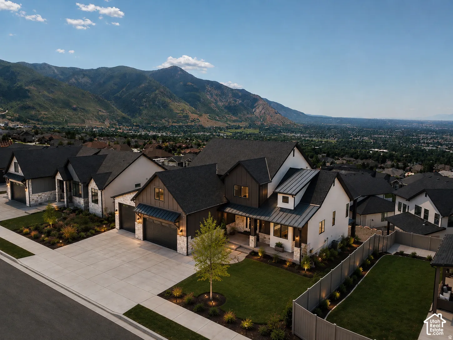 Modern farmhouse estate featuring a striking two-story façade with mixed exterior finishes, gabled rooflines with dark asphalt shingles, and a prominent front-loading garage