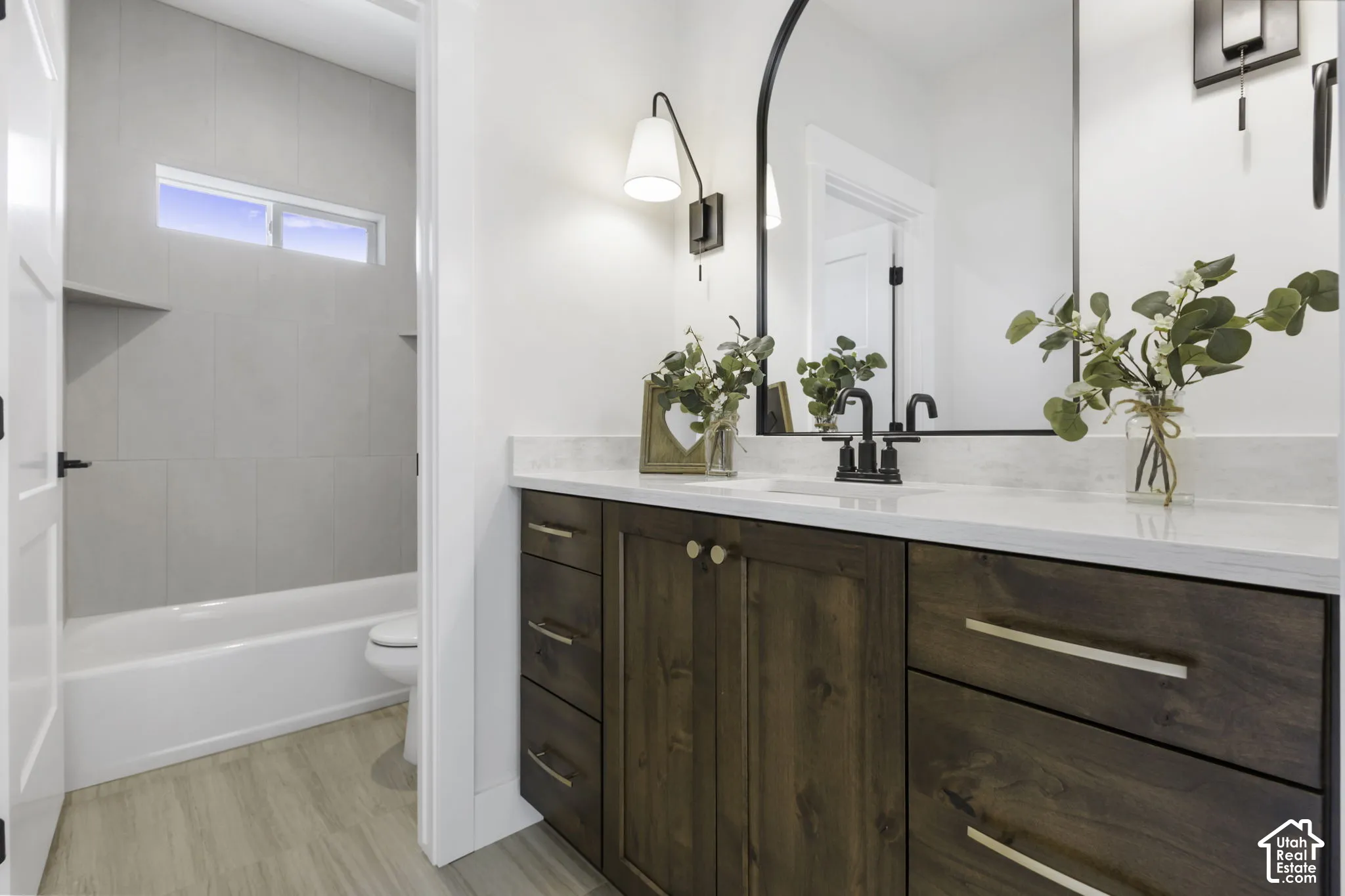 Rich wood-finish vanity with gold-tone hardware, white countertop, and black-finish faucet