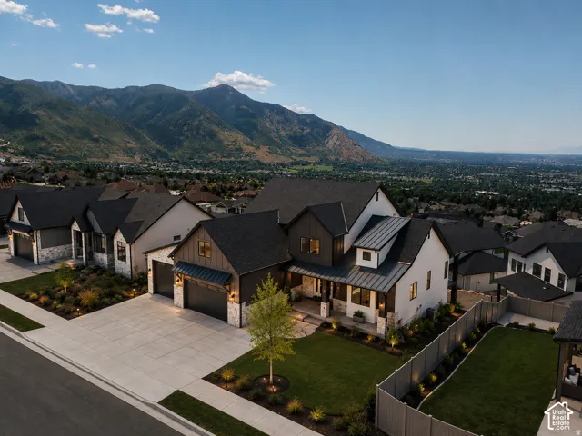 Modern farmhouse estate featuring a striking two-story façade with mixed exterior finishes, gabled rooflines with dark asphalt shingles, and a prominent front-loading garage