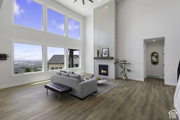 Soaring ceilings with transom windows, a floor-to-ceiling fireplace featuring herringbone tile and a timber mantel, and wood-finish flooring