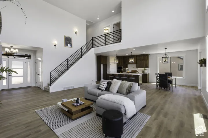 Two-story living area with high ceilings, wood-finish flooring, and a modern staircase with black metal railings
