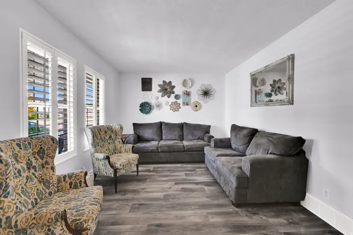 Light-filled room featuring multiple windows with plantation shutters, wood-finish flooring, and white walls