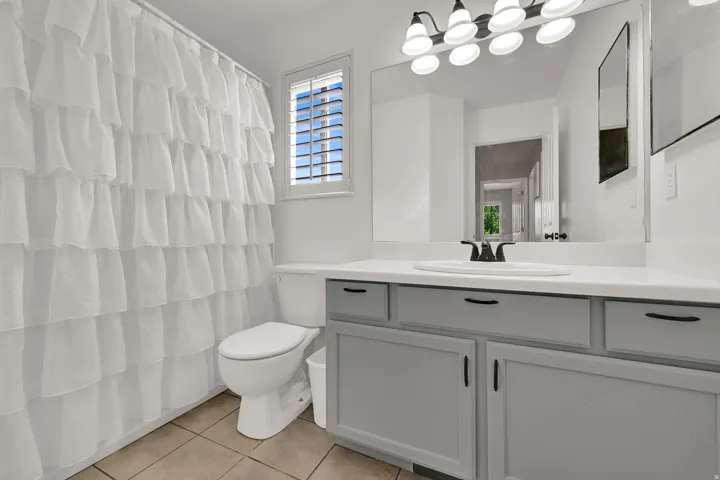 White vanity countertop with an integrated sink, matte black faucet, and gray cabinetry