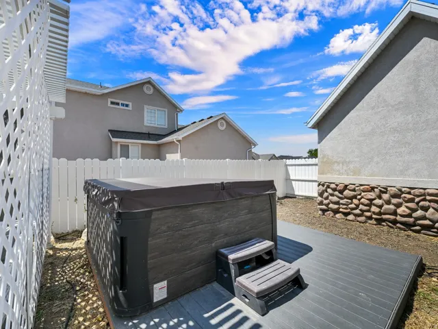 Outdoor spa with a cover, composite decking, and a white privacy fence
