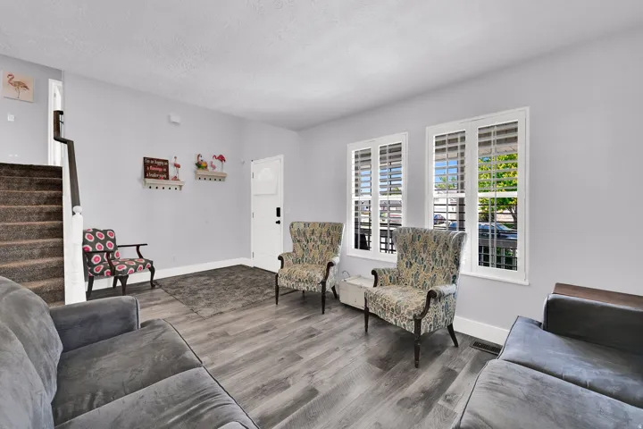 Wood-finish flooring, white trim, plantation shutters, painted walls, and a carpeted staircase