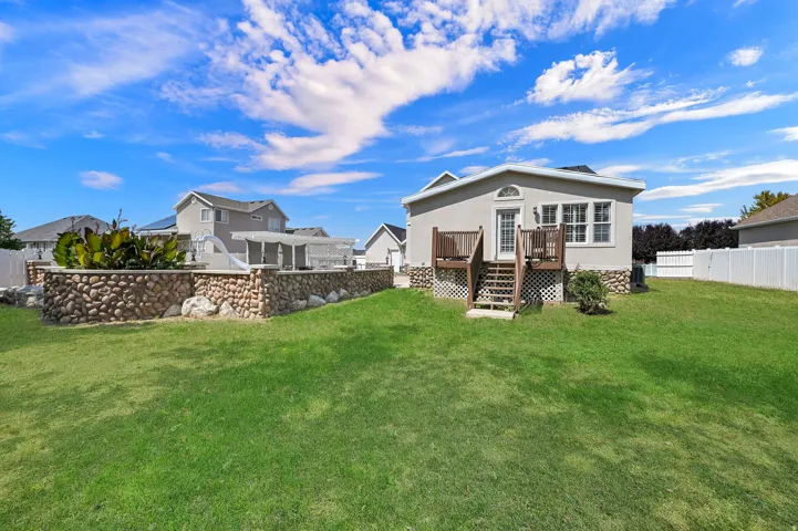 Expansive grass lawn with a stone retaining wall and a white fence