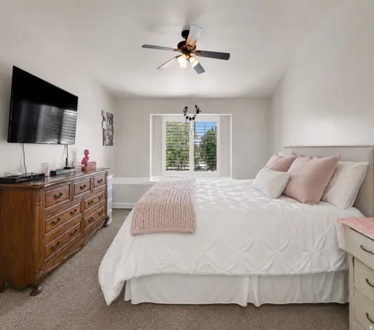 Carpeted flooring, window with plantation shutters, ceiling fan with integrated lighting, built-in window bench