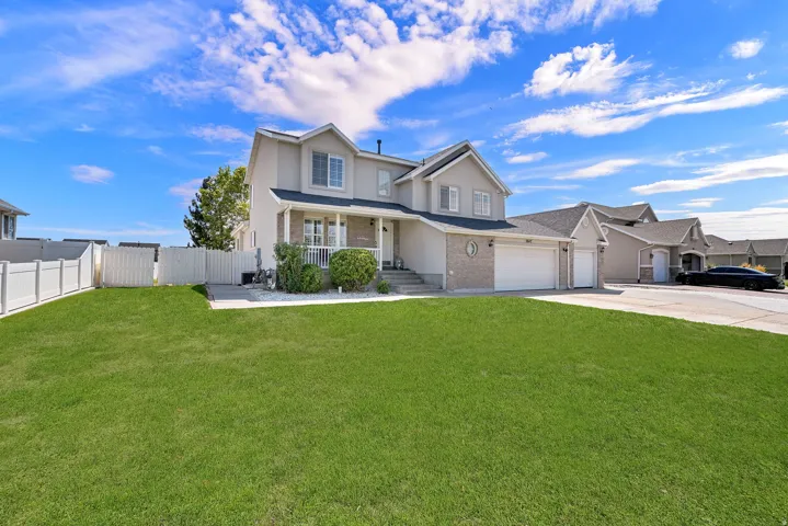 Two-story exterior with a two-car garage, white fencing, and a front lawn