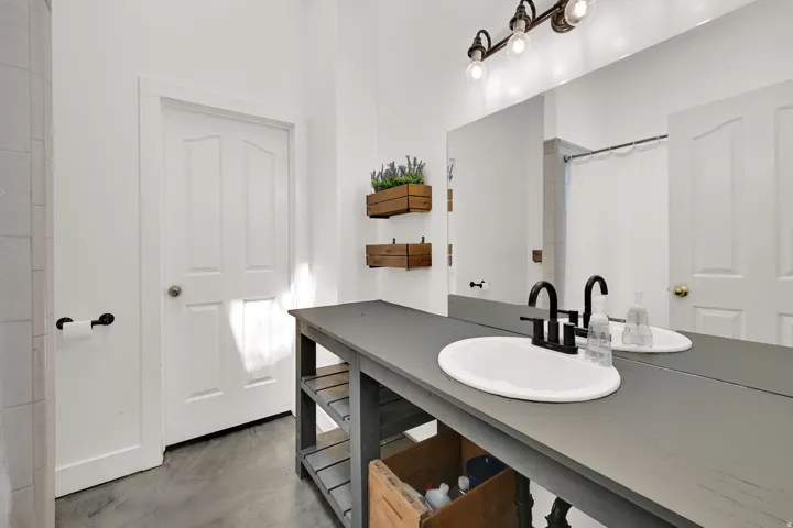Open vanity with a rectangular sink, matte black faucet, and large wall-mounted mirror