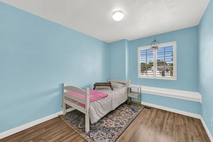 Recessed window with plantation shutters, wood-finish flooring, light blue wall paint, and built-in window bench