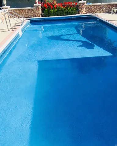 In-ground swimming pool featuring a curved entry staircase and stainless steel handrails