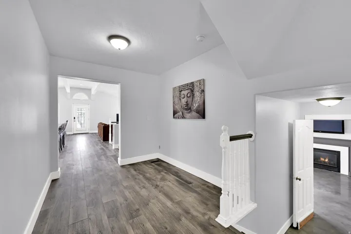 Wood-finish flooring throughout, vaulted ceiling, white trim, and a built-in fireplace feature