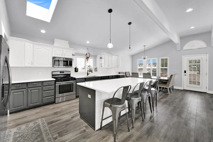 Stainless steel appliances, wood-finish flooring, skylight, vaulted ceiling, and recessed lighting