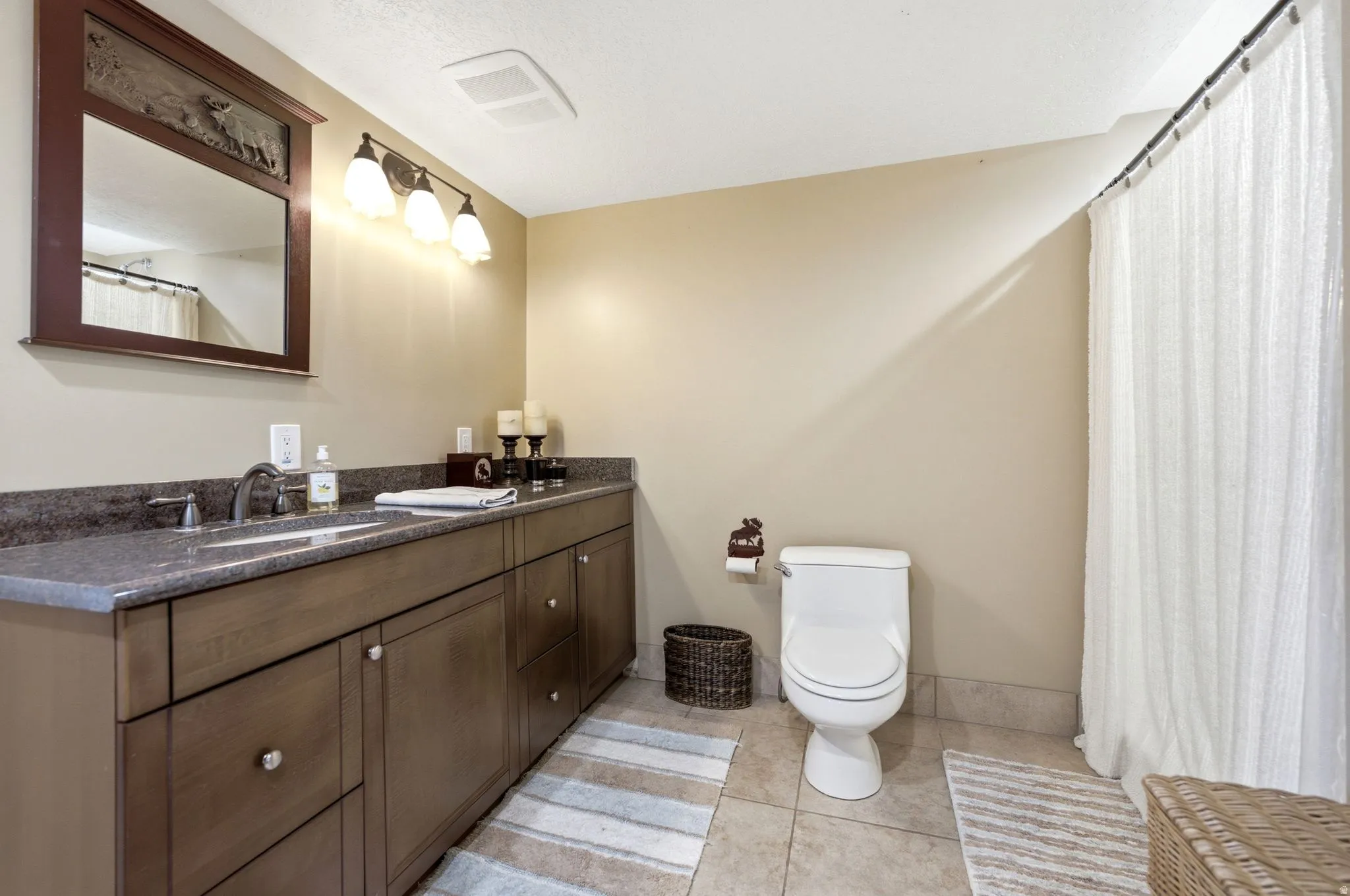 Extended vanity with an integrated sink, dark countertop, and wood-finish cabinetry