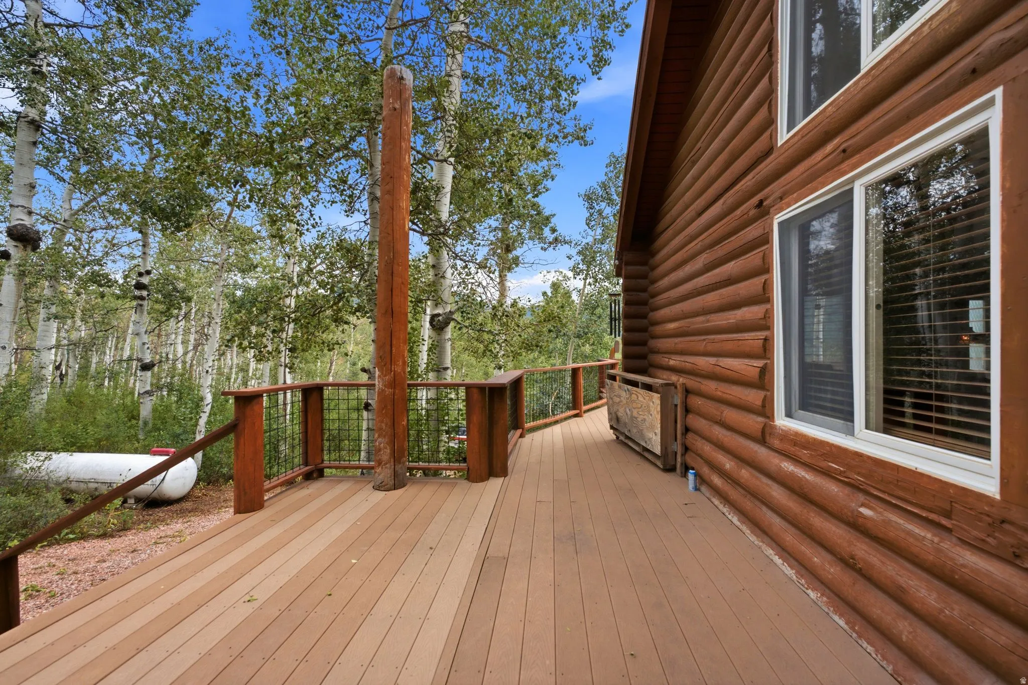 Expansive wood-finish deck with wood railings, featuring a log-style exterior and multiple windows