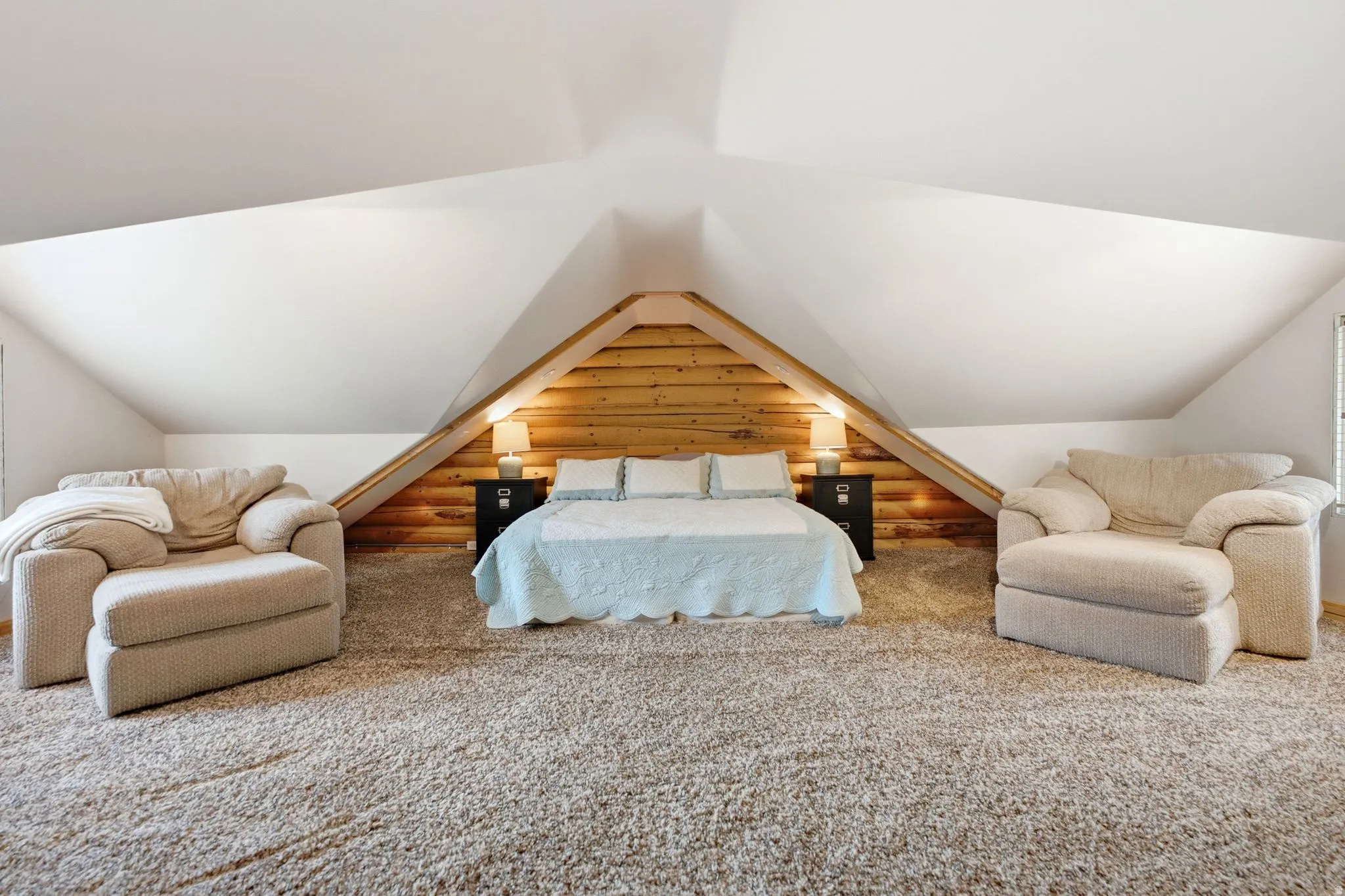 Vaulted ceiling with angled walls, wood-paneled accent wall, and built-in bedside tables
