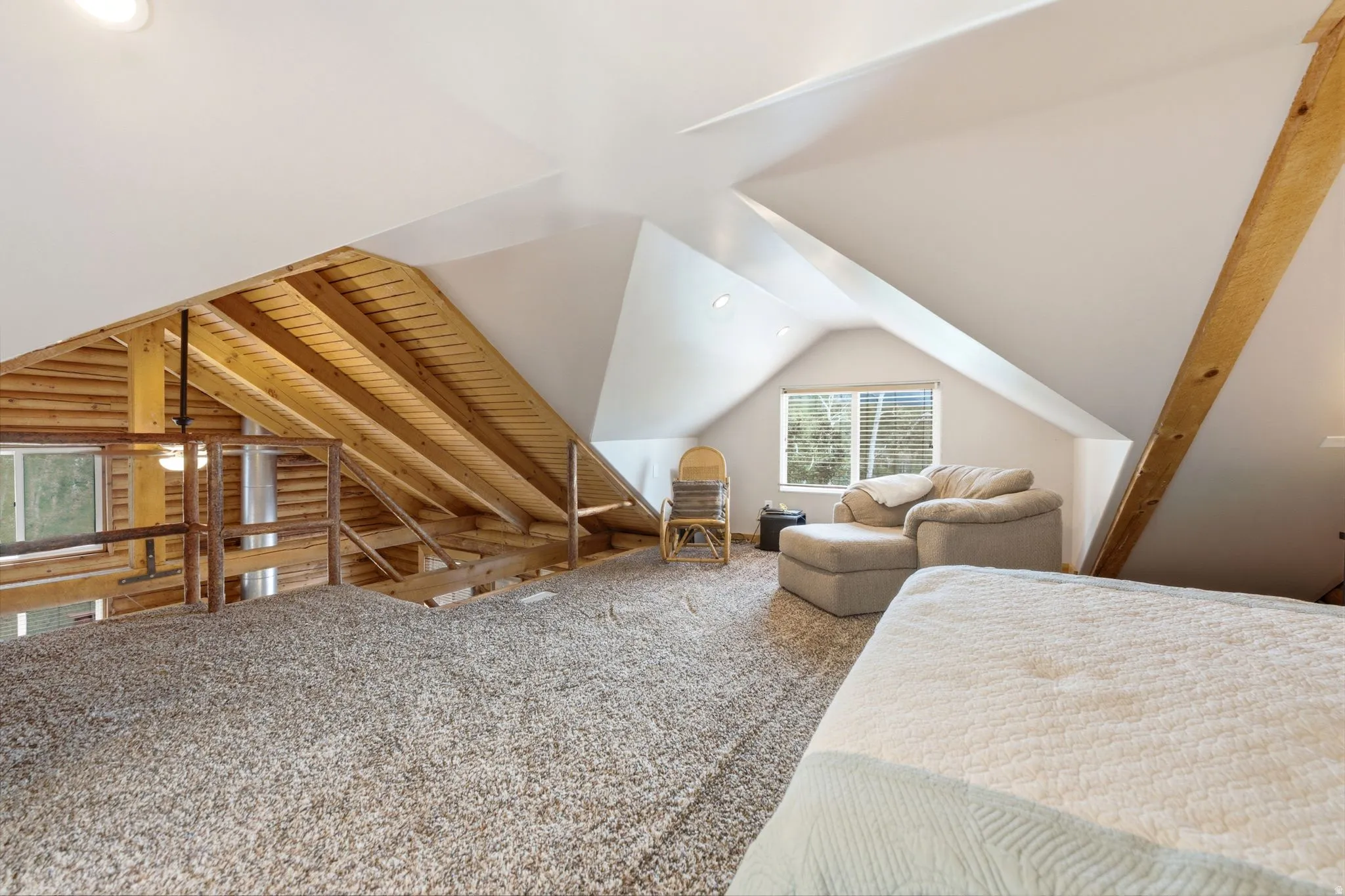 Angled ceilings, exposed wood beams, and a window with blinds