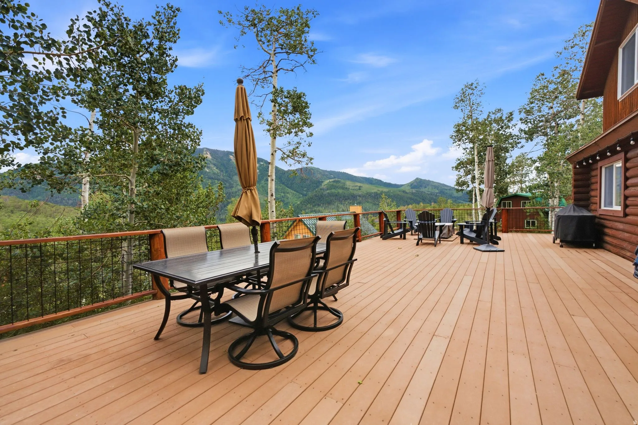 Expansive outdoor deck with mountain scenery, wood-finish decking, and black metal railing
