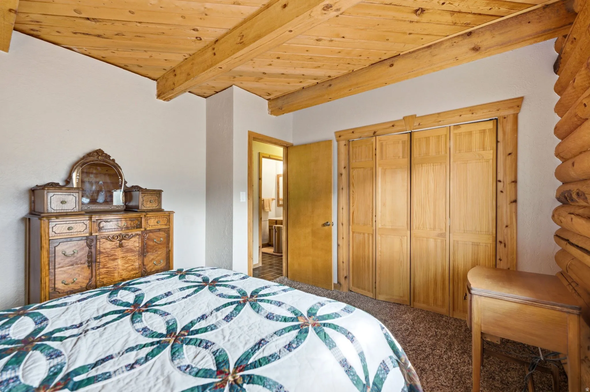 Exposed wood beam ceiling, natural wood paneling, and wood bi-fold closet doors