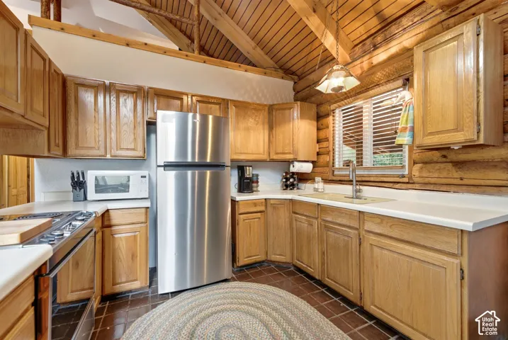 Kitchen with wood cabinetry, white countertops, stainless steel appliances, and a wood-paneled ceiling