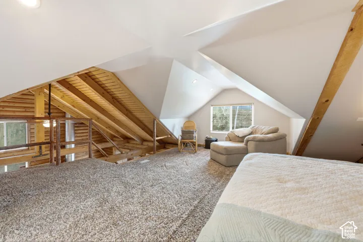 Angled ceilings, exposed wood beams, and a window with blinds
