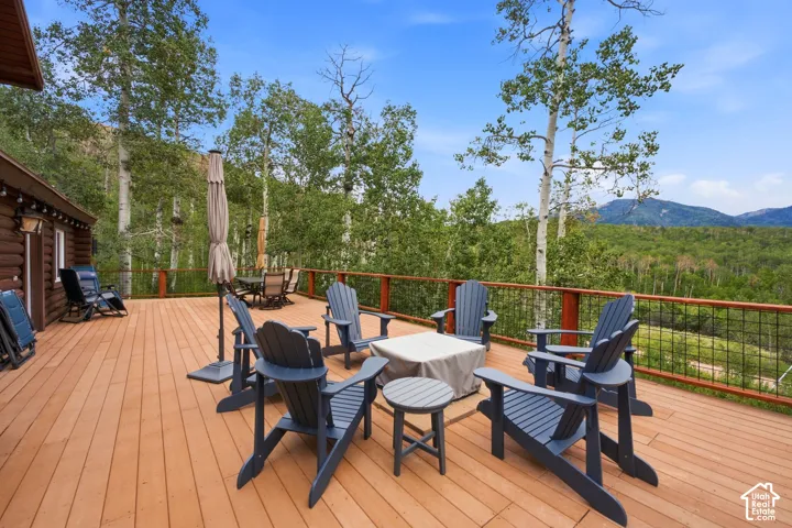 Spacious outdoor deck with wood-finish flooring, metal railing, and a rustic log cabin exterior