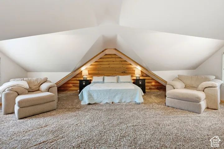 Vaulted ceiling with angled walls, wood-paneled accent wall, and built-in bedside tables