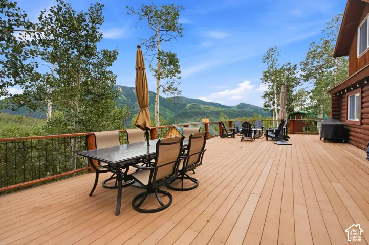 Expansive outdoor deck with mountain scenery, wood-finish decking, and black metal railing