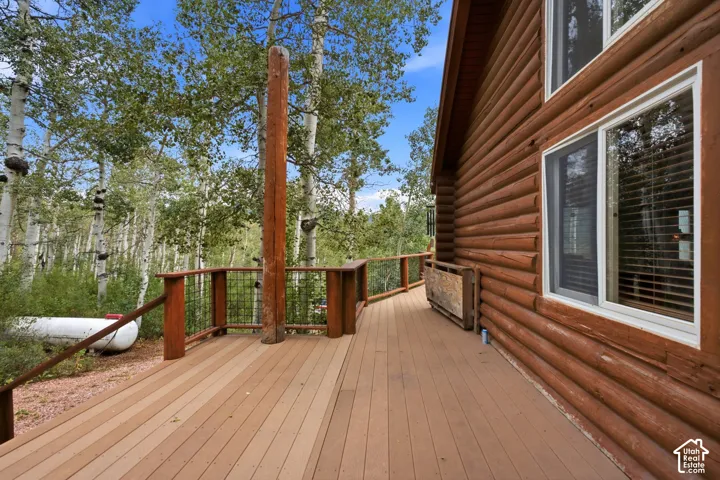 Expansive wood-finish deck with wood railings, featuring a log-style exterior and multiple windows