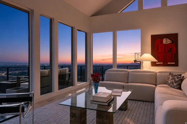 Expansive windows, high vaulted ceilings, and a glass coffee table