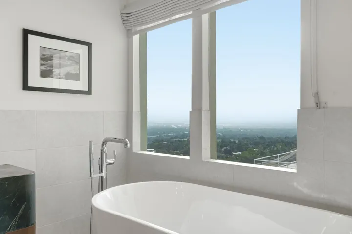 Freestanding soaking tub with a floor-mounted polished chrome faucet, set against a tiled wall