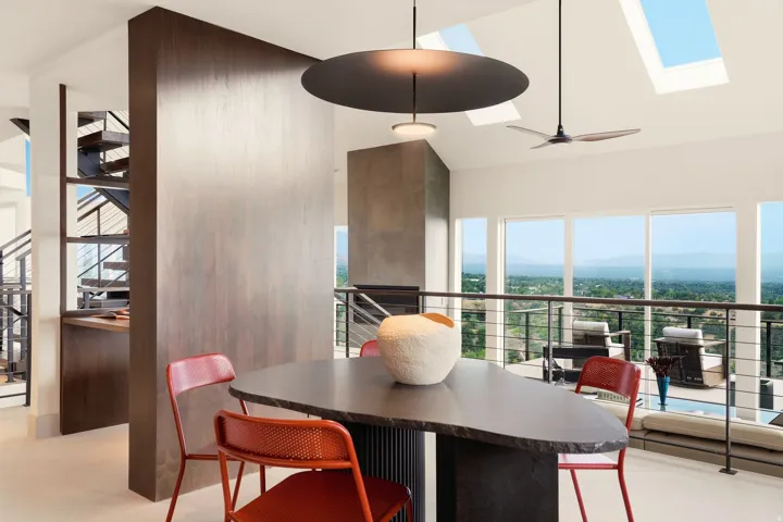 Vaulted ceiling with skylights, large format windows, built-in shelving, dark wood-finish wall paneling, and a contemporary dining surface