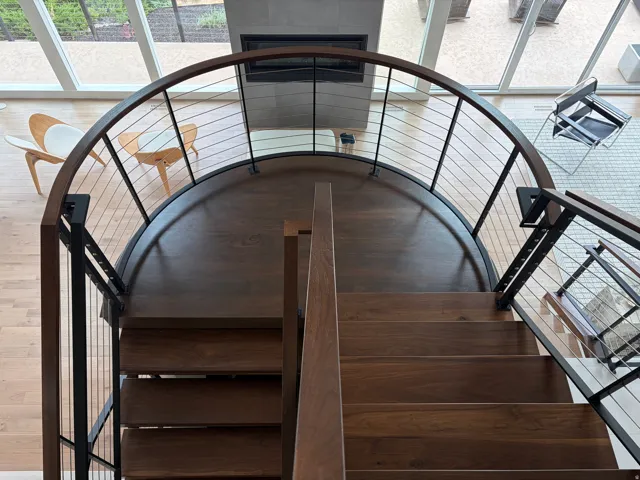 Curved staircase featuring wood treads and a cable railing system