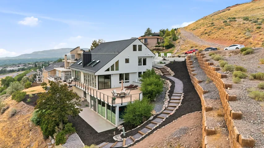 Modern architectural design with multiple-level decking, extensive landscaping, and a terraced hillside