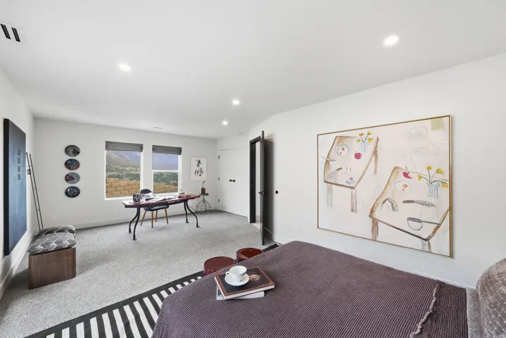 Recessed ceiling lighting illuminates a spacious room featuring wall-to-wall carpeting and multiple windows