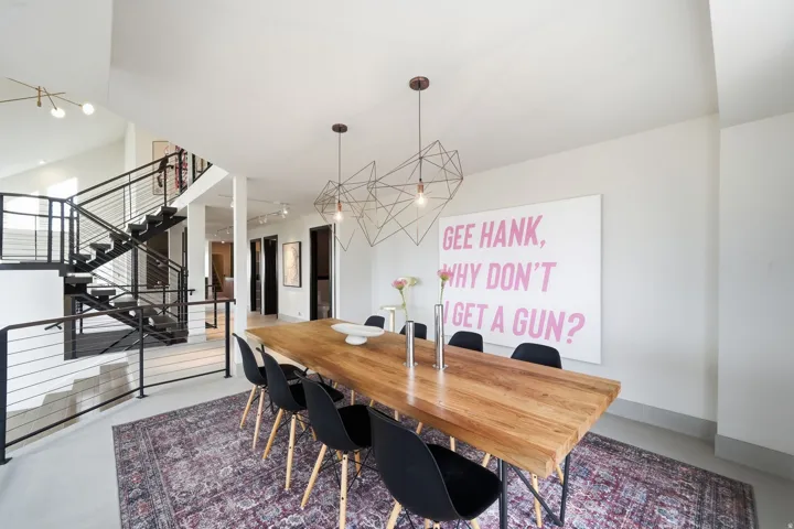 Open-concept dining area with high ceilings, contemporary geometric pendant lighting, and a prominent staircase with metal railings