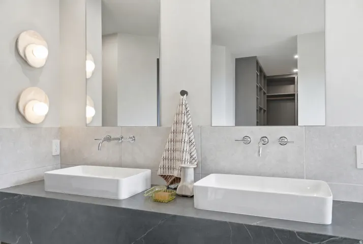 Double vanity with rectangular vessel sinks, wall-mounted faucets, and a dark stone countertop