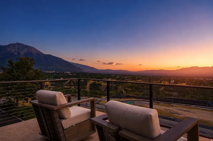 Balcony with metal railing and cable infill, featuring a expansive mountain backdrop and distant urban scenery