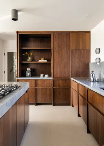 Integrated wood cabinetry, light-toned tile flooring, light-colored countertops with veining, and a built-in gas range