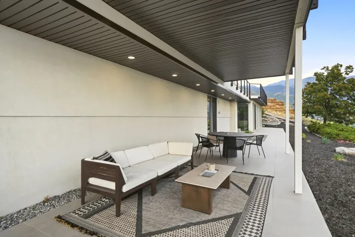 Covered patio featuring recessed lighting, a smooth concrete floor, and a black metal railing
