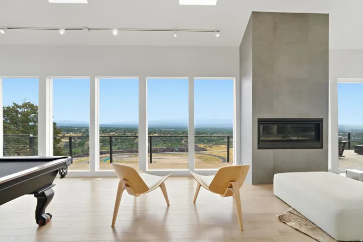 Floor-to-ceiling windows, light wood-finish flooring, recessed lighting, skylights, and a built-in fireplace with a tiled surround