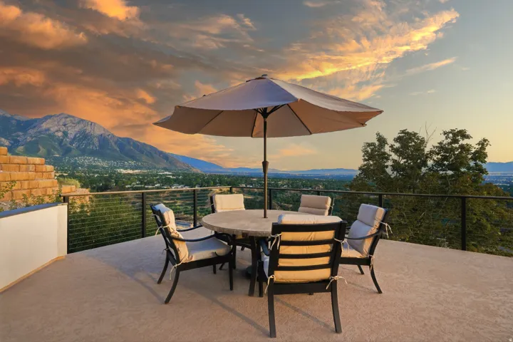 Expansive outdoor patio with mountain and city scenery, featuring a cable railing system and a low retaining wall